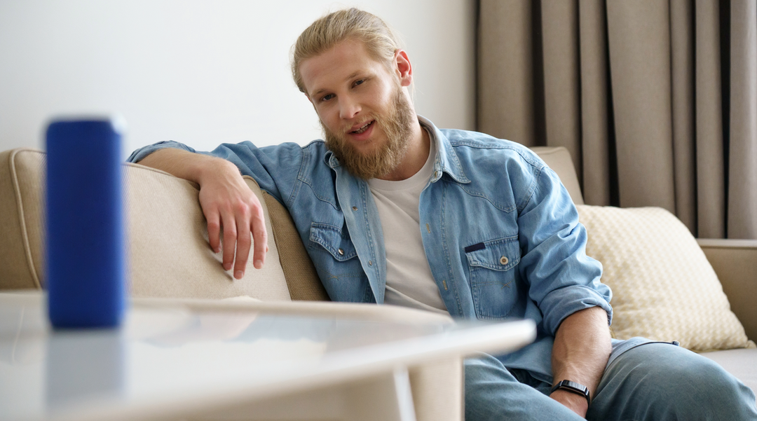 Blue speaker on table with man in the background - small speaker -cheap speakers