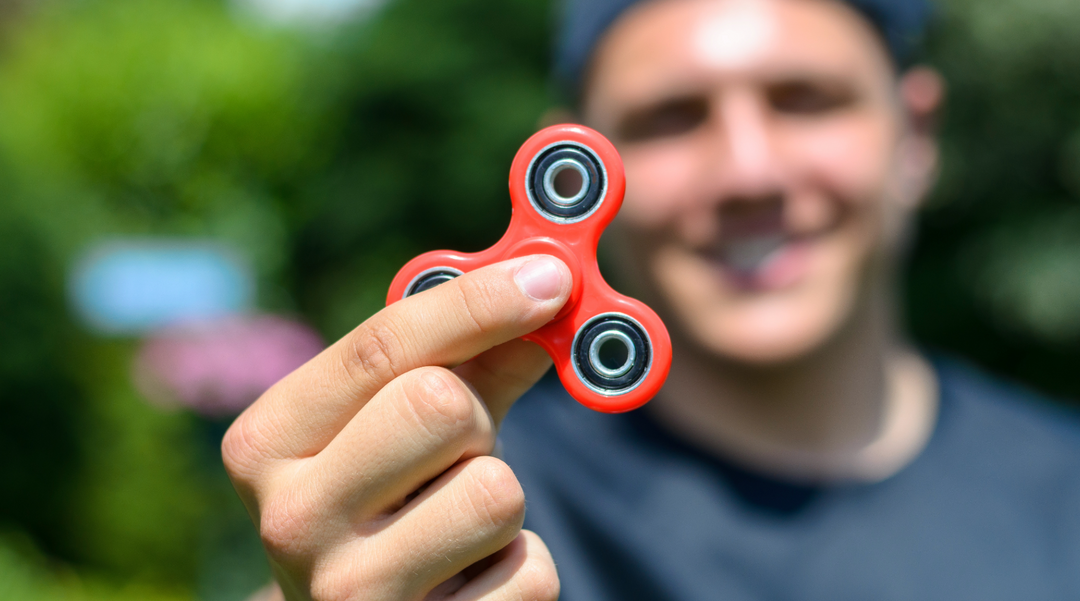 Man holding up red fidget spinner - fidget spinner - novelty gifts